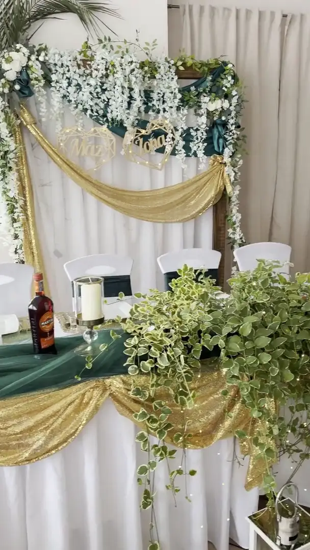 Stół pary młodej ze ścianką kwiatową i złotą draperią