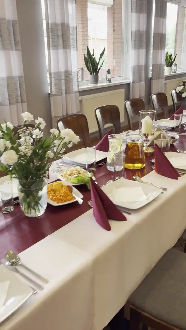 Stół z bordowymi serwetkami i bukietami białych kwiatów