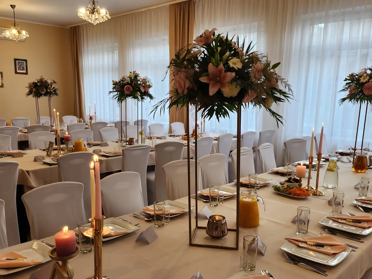 Sala weselna z nakrytymi stołami i wysokimi kompozycjami kwiatowymi w hotelu Dowhań